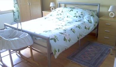 Double bed with bedside tables and baby moses basket