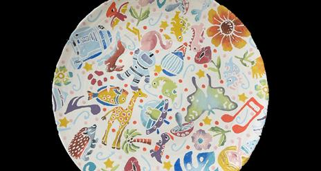 round hand thrown plate with printed shapes on it such as flowers, leaves, tiny dinosaurs, spacemen, aliens, music notes and animals. Printed in lots