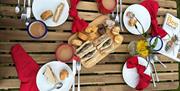 A picnic table laid out with plates, cutlery and food