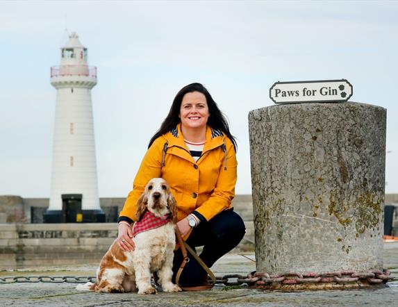 a photo of a woman and a dog in front of donaghadee lighthouse