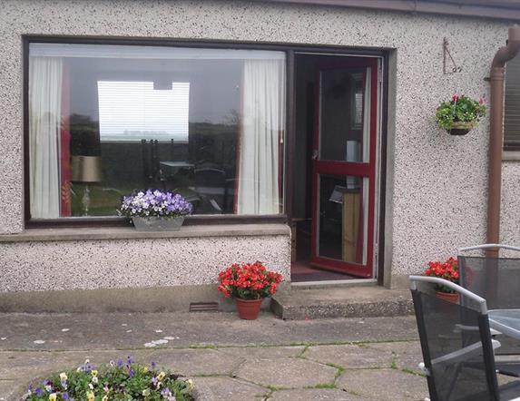Photo of entrance to accommodation and seating area in yard