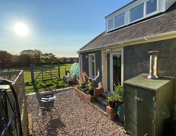 Photo of outside of the accommodation with fields, blue sky and sunshine