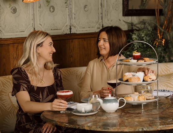 Blonde female and brunette female eating afternoon tea at the old inn