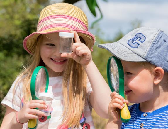 Two children looking through magnifying glasses.
