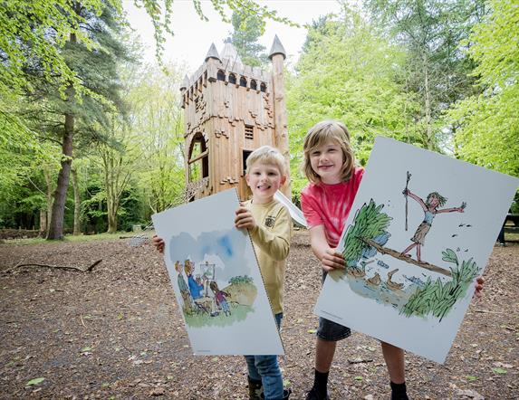Two children holding poster boards of illustrations by Quentin Blake, in the grounds of WWT Castle Espie