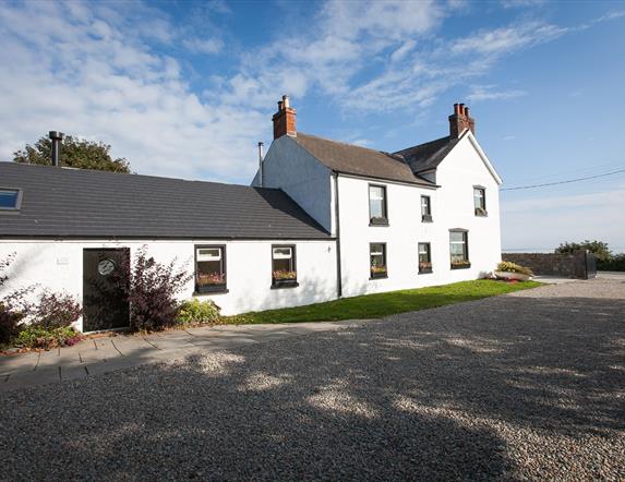 Exterior view of a segmented white house with a large stone driveway.