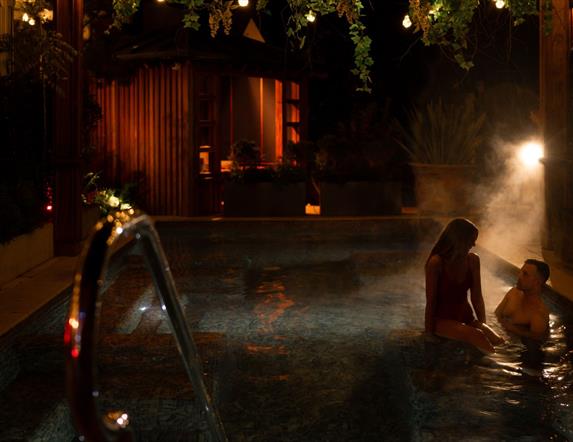 female and male in an outdoor heated pool in The Treetop Spa