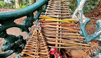WILLOW CHRISTMAS TREES SITTING ON A GARDEN BENCH