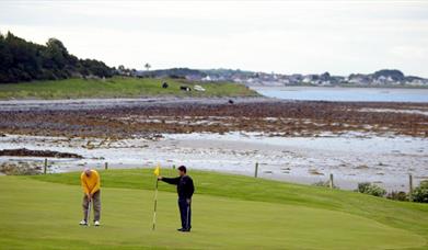 Photo of two golfers in play with stunning scenery to the background