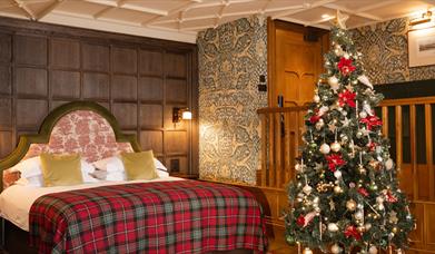 Junior suite with a large bed with checkered bedding and a christmas tree
