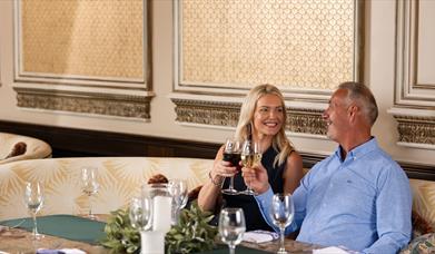 Female and male sitting in the gallery of the old inn cheering with wine glasses