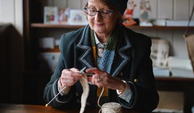 a LADY DRESSED IN HISTORICAL COSTUME KNITTING