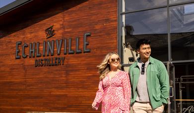 Couple walks outside the Echlinville Distillery in the sunshine