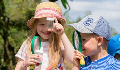 Two children looking through magnifying glasses.