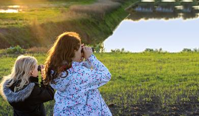 two young girls looking through binoculars over the wetlands