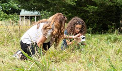 Two people taking photos in nature using a polaroid camera