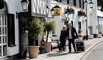 A couple pulling overnight bags entering into The Old Inn