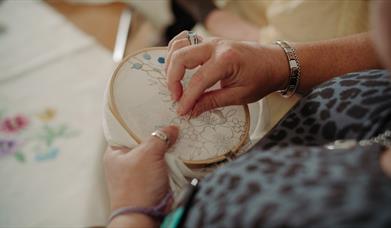 A lady using a hoop to embroider