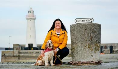 a photo of a woman and a dog in front of donaghadee lighthouse