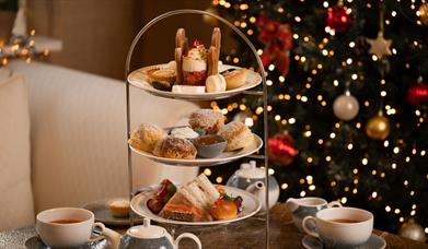 Festive afternoon tea set up with christmas tree in background