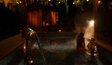 female and male in an outdoor heated pool in The Treetop Spa 