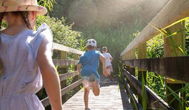 Children running across a bridge in the summer sun at the wetlands.