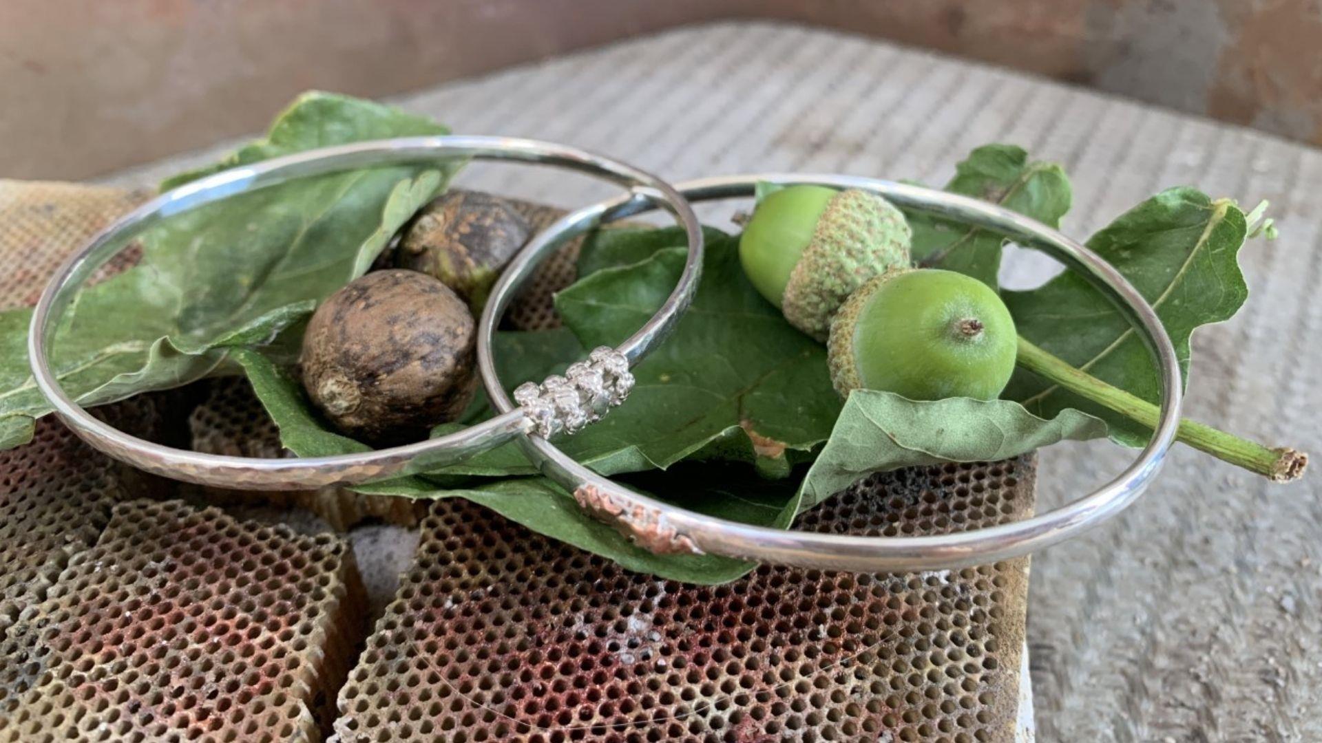 a photograph of 2 silver bangles with leaves and acorns