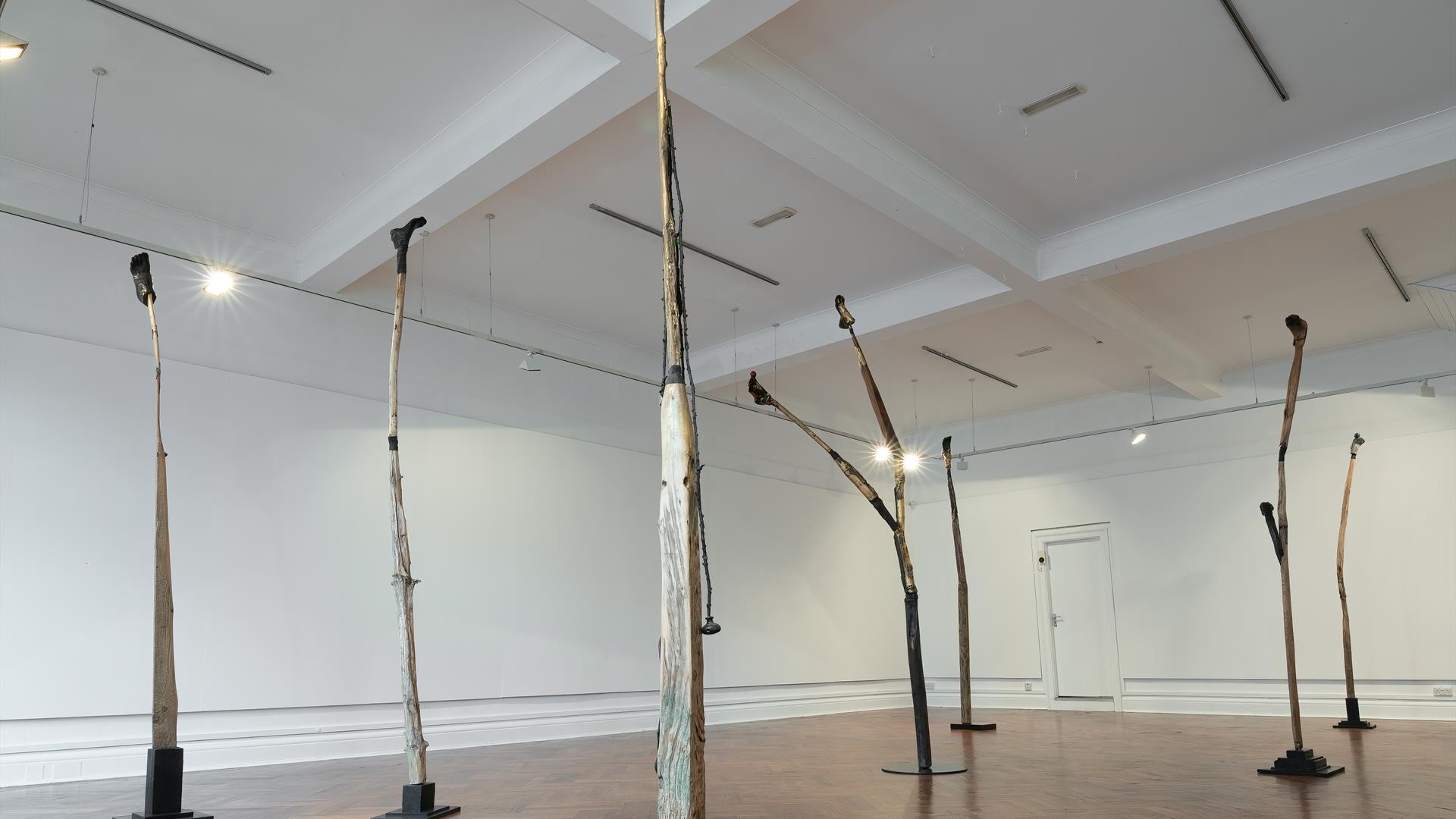 A group of tall sculptures reaching towards the ceiling in a gallery