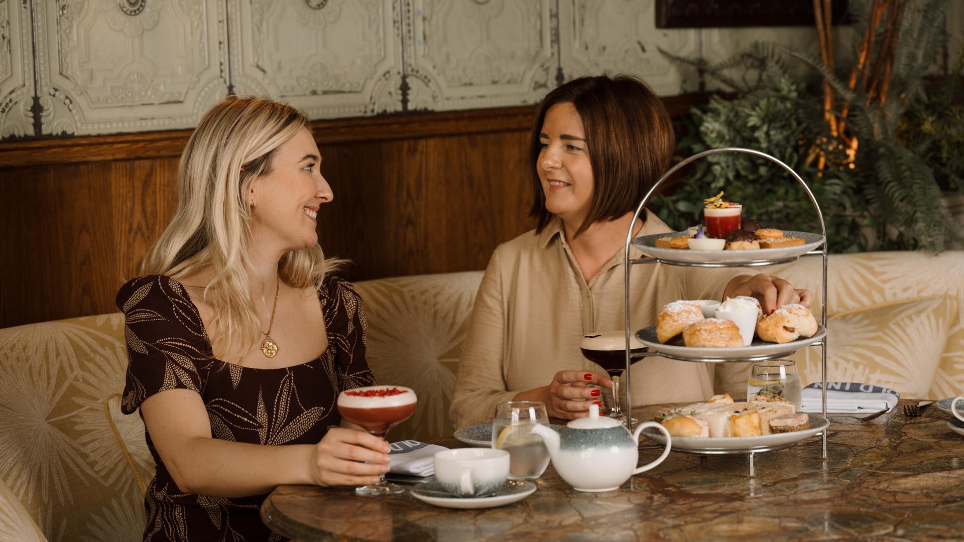 Blonde female and brunette female eating afternoon tea at the old inn