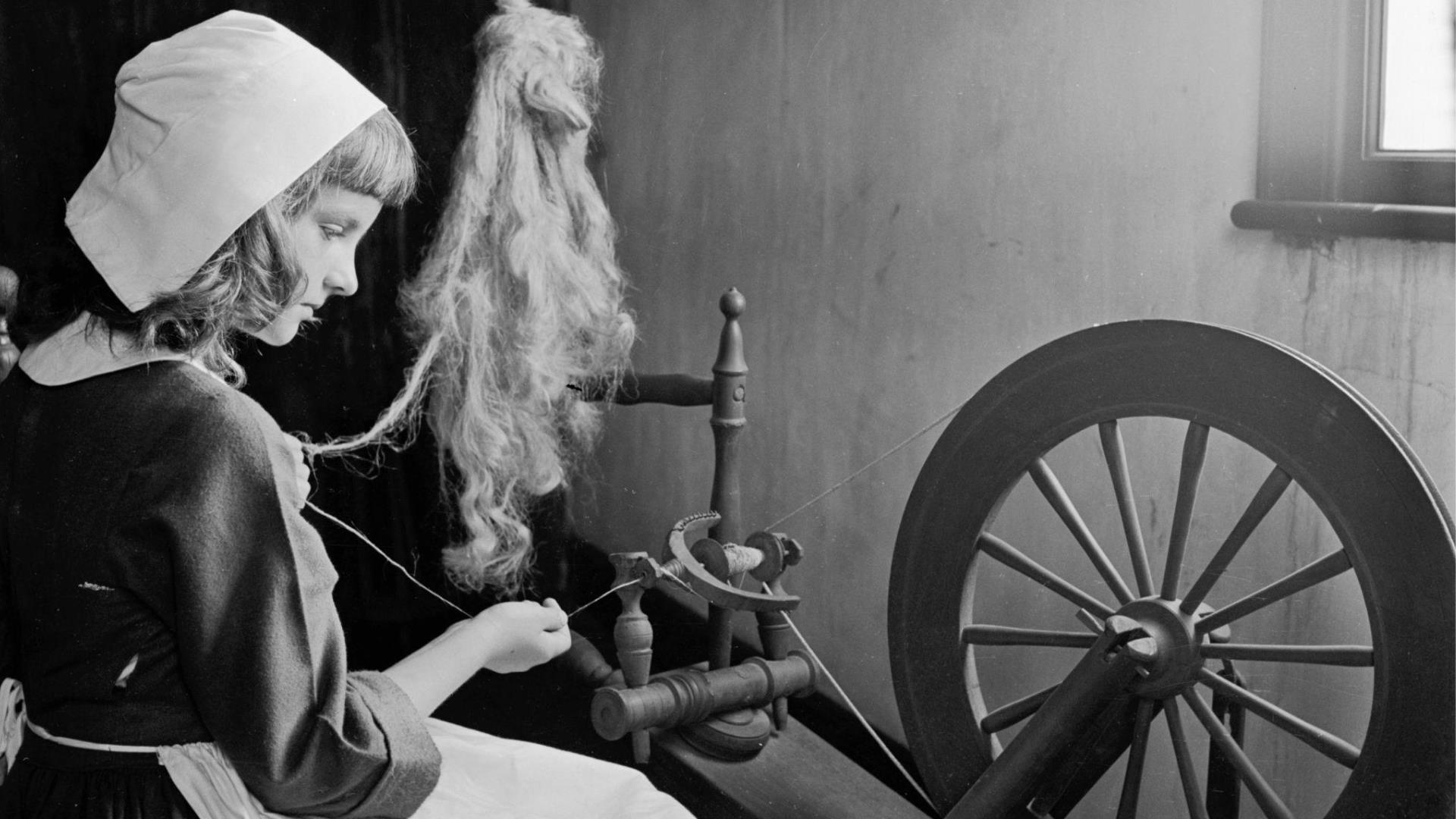 A girl sat at a spinning wheel, spinning