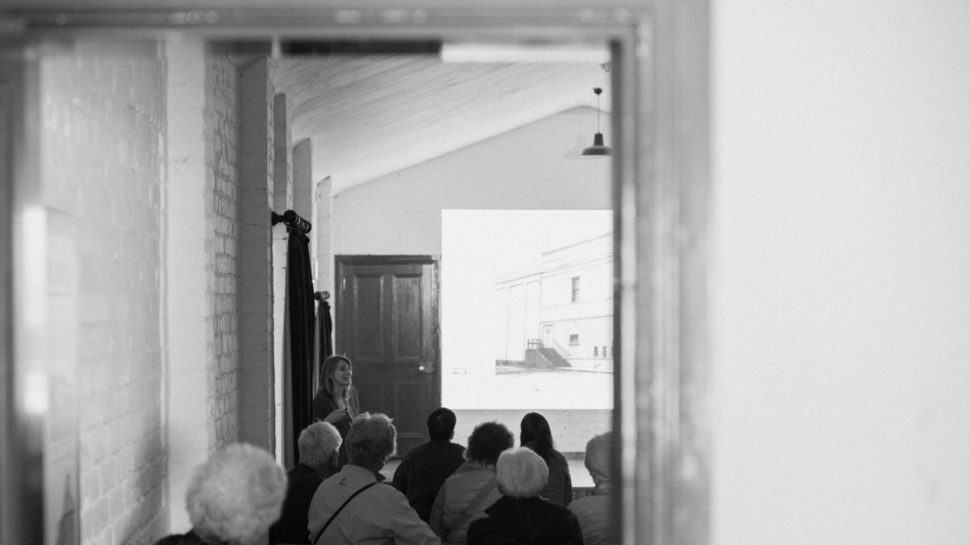 A black and white image of a woman giving a lecture