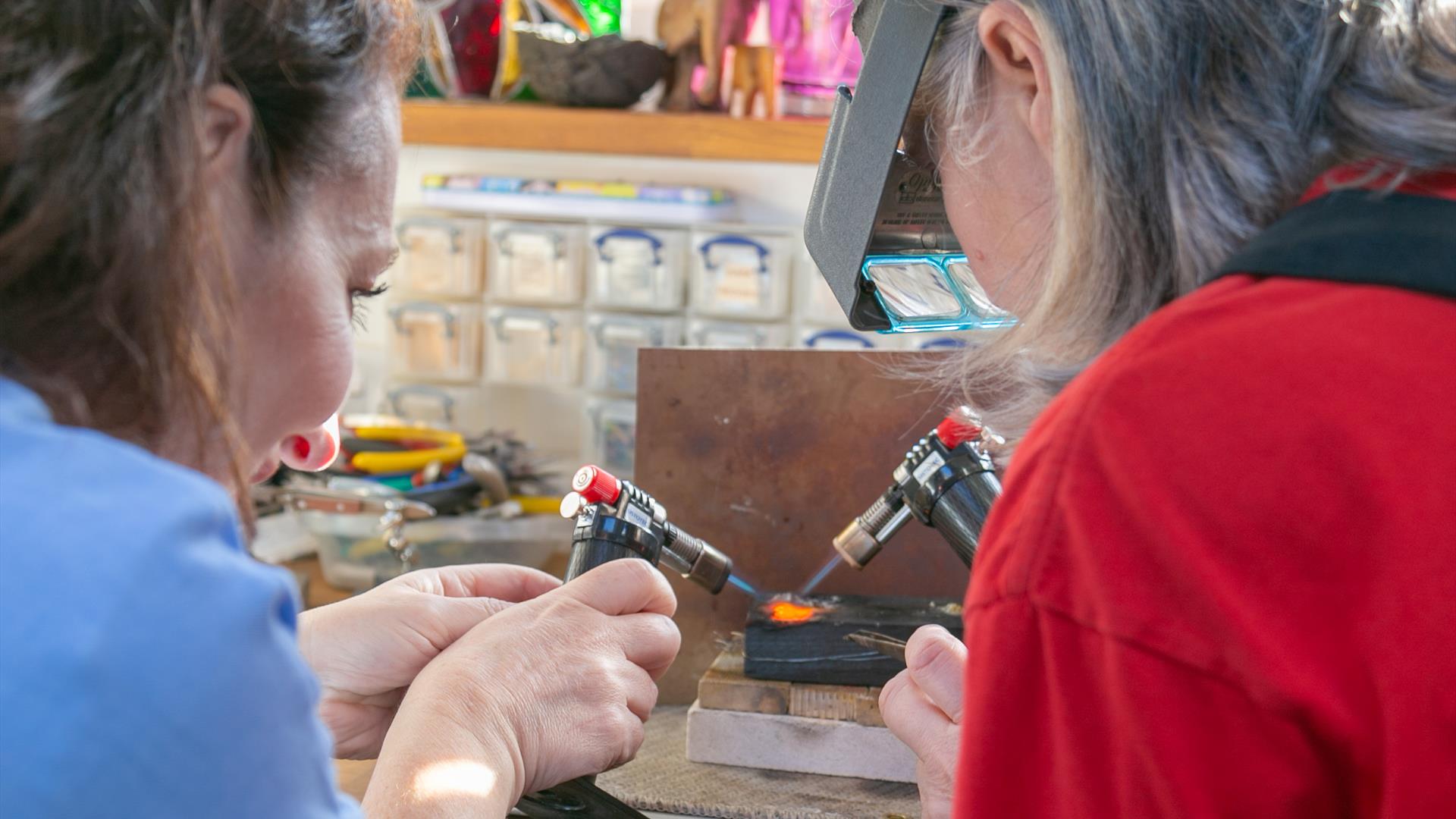 Two ladies with small torches melting down some gold in contemporary studio