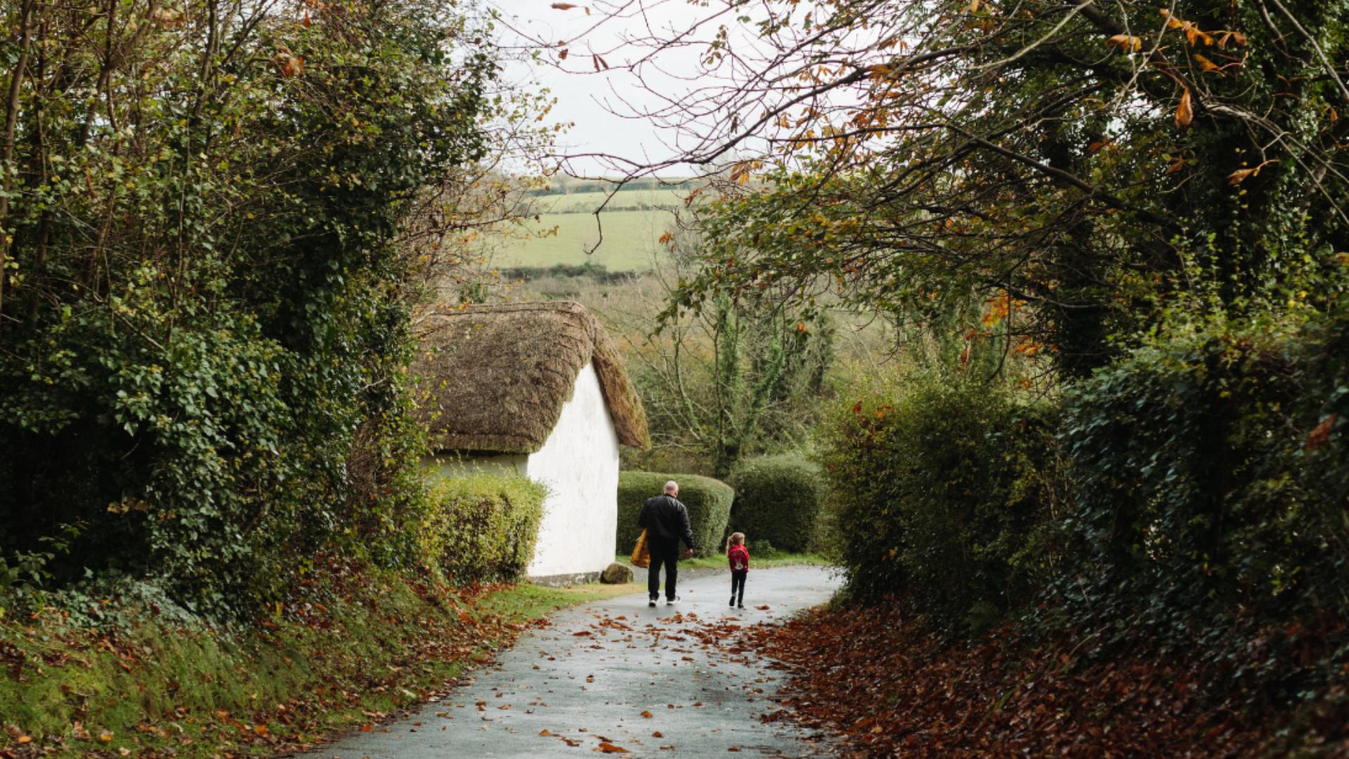 A man and child walking down a rural autumnal lane