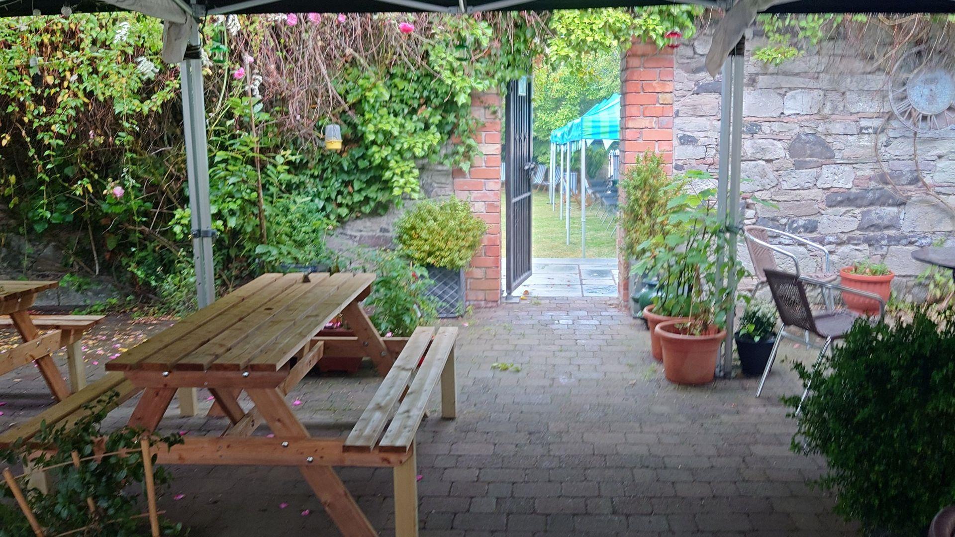 Exterior of No. 14 Georgian House Comber, looking from Courtyard into the Walled Garden, with picnic benches and shrubbery in view