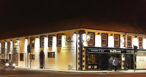 Front exterior of restaurant lit up at night