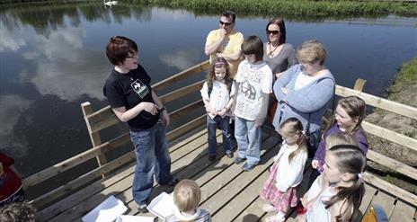a photograph of a group of people standing next to a lake