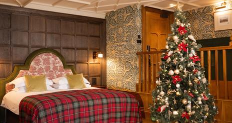 Junior suite with a large bed with checkered bedding and a christmas tree
