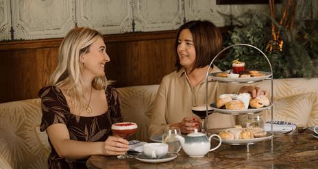 Blonde female and brunette female eating afternoon tea at the old inn