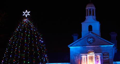 A photograph of Newtownards Christmas Tree lit at night with Ards Arts Centre in the backdrop