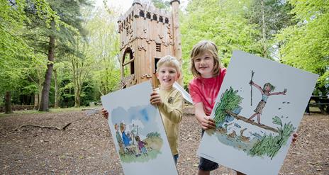 Two children holding poster boards of illustrations by Quentin Blake, in the grounds of WWT Castle Espie