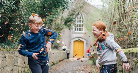 Children enjoying the autumn leaves in the museum grounds
