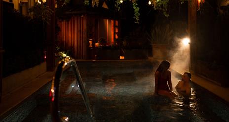 female and male in an outdoor heated pool in The Treetop Spa
