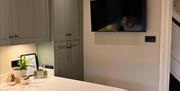 Kitchen breakfast bar with stools and wall-mounted TV.