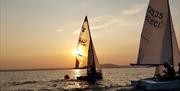 Two small sailing boats on the water at sunset