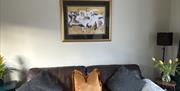 Leather sofa with cushions beneath framed wall art.