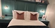 Double bedroom with teal panelled headboard and bedside lighting