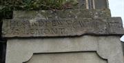 A close up photo of one of the stone entrance pillars to the church with the names Thomas Andrews and Ja Lemont, eighteenth century churchwardens,