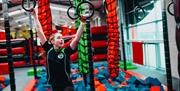 Girl Swinging off hanging hoops at Airtastic Ninja Park