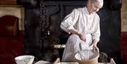 a photograph of a woman in old maid's clothing doing some baking