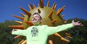 A child posing happily in from of one of the Our place in space planet sculptures